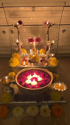 candles are lit in a bowl with flowers on the floor next to it and other decorations