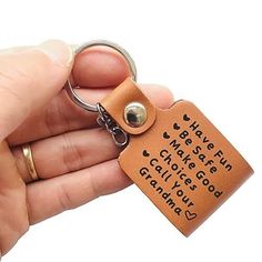 a hand holding a leather keychain with words on it