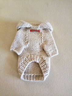 a white knitted sweater with a bow on the front and bottom is laying down