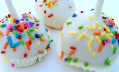 three white cake pops with sprinkles on them