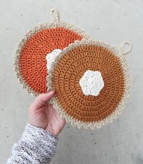 two crocheted coasters are shown in the shape of an orange and white circle