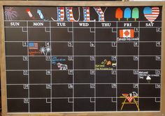 a chalk board with an image of july written on it and colorful magnets attached to the calendar