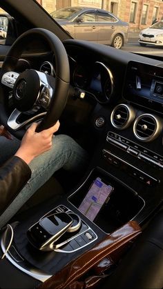 a person is sitting in the driver's seat of a car while using their cell phone