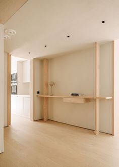 an empty room with wooden floors and shelves on the wall, along with a lamp