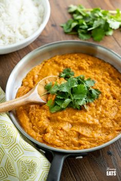 a wooden spoon in a pan filled with food and garnished with cilantro