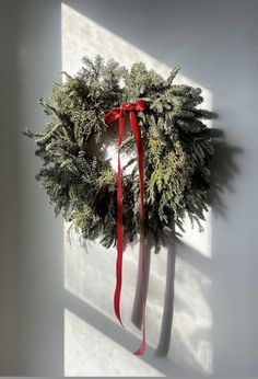 a wreath hanging on the wall with a red ribbon