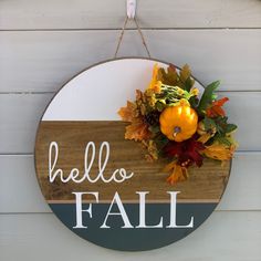 a sign that says hello fall hanging on the side of a building with leaves and flowers