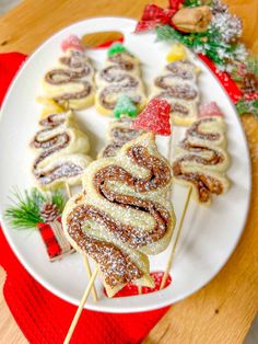 a white plate topped with pastries covered in powdered sugar and surrounded by christmas decorations