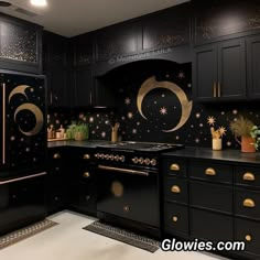 a kitchen with black cabinets and gold stars painted on the backsplash, along with potted plants