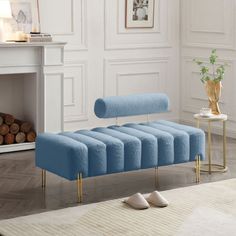 a blue bench sitting on top of a wooden floor next to a fire place in a living room