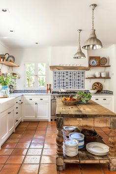 a kitchen with white cabinets and an island in front of the counter top that has plates on it