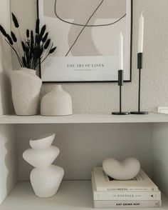 two white vases and some books on a shelf