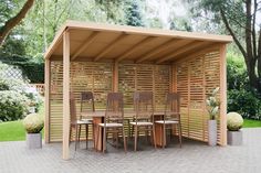 a wooden table and chairs under a pergolated area