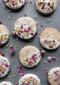 several cookies with white frosting and sprinkles on a baking sheet covered in flowers