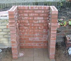 an outdoor brick fire pit in the middle of a yard with bricks and cement around it