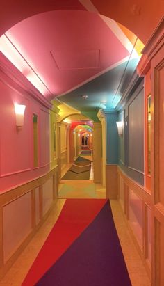 the hallway is brightly lit and has colorful carpeting on both sides, along with pink walls