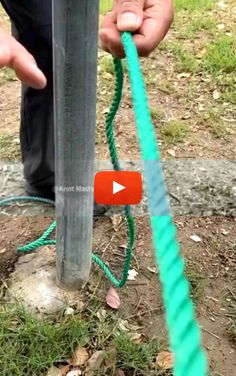 a person holding a green rope attached to a metal pole with two hands on it