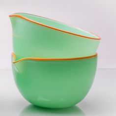 two green bowls sitting side by side on a white surface