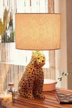 a cheetah lamp sitting on top of a wooden table next to a book