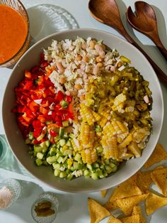 a white bowl filled with different types of food next to tortilla chips and salsa