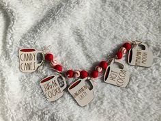 some red beads and silver tags are on a white blanket with the words candy cane