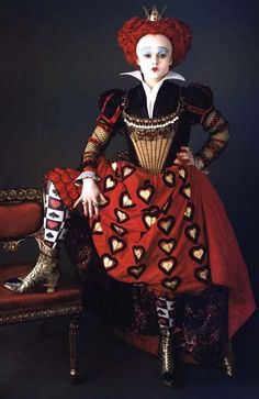 a woman sitting on top of a chair wearing a red and black dress with hearts