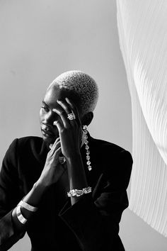 a woman talking on a cell phone while wearing a suit and bracelets with her hand to her ear