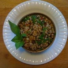 a white plate topped with a bowl of food on top of a wooden table next to a green leaf