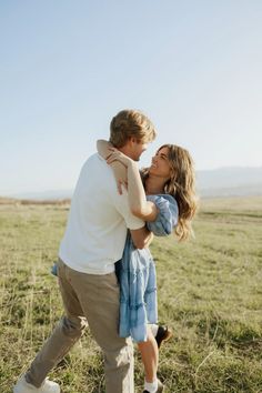 a man and woman kissing in the middle of a field