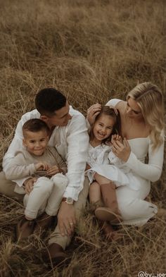 a family is sitting in the tall grass together