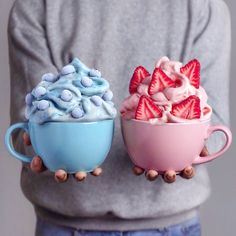 two cups filled with whipped cream and strawberries on top of each other in front of a person's stomach