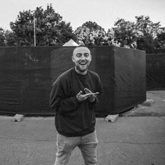 black and white photograph of a man standing in front of a fence holding a cell phone