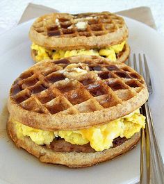 two waffles with eggs and bacon on them sitting on a plate next to a fork