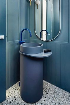 a bathroom with blue walls and a round mirror