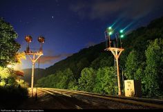 a train track with some lights on it and trees in the background at night time