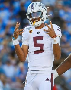 a close up of a football player holding his hands out to the sidelines with one hand