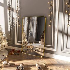 a mirror sitting on top of a wooden floor next to a christmas tree with lights