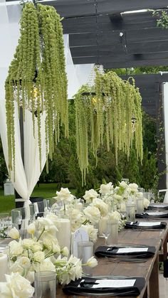 a long table is set with black and white place settings for an outdoor wedding reception