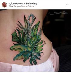 a woman's lower back tattoo with green leaves