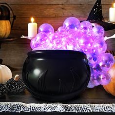 a black caulder filled with purple lights and pumpkins next to other halloween decorations