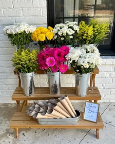 flowers are arranged in metal buckets on a wooden stand with a sign that says love