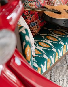 a red scooter sitting on top of a carpet covered floor next to pillows