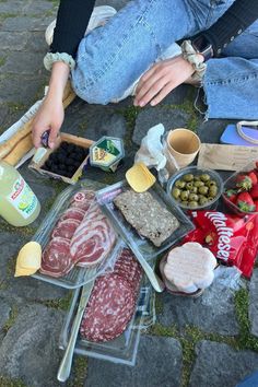 a person sitting on the ground with food and condiments in front of them