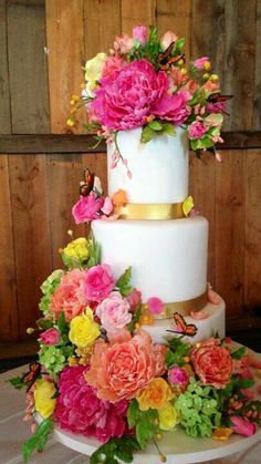 a three tiered white cake with pink and yellow flowers