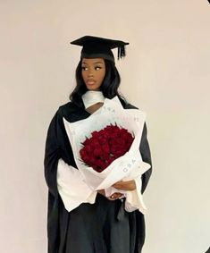 a doll dressed as a graduate holding a bouquet of red roses in her hands and wearing a black cap and gown