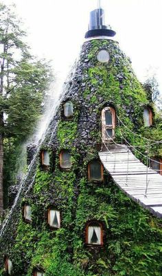 a very unusual house made out of plants and water spouting from the roof