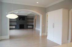 an empty living room with white cabinets and wood flooring in the middle of it