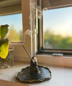 a incense stick sitting on top of a black plate next to a window sill