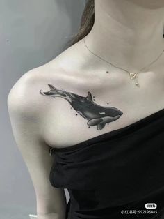 a woman with a tattoo on her chest and an orca whale in the water