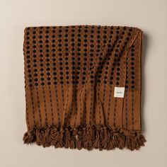 a brown and black patterned blanket with fringes